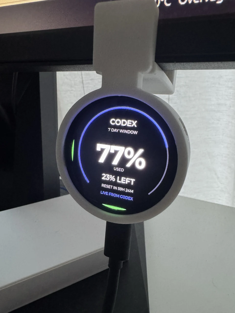 Round Codex display in its monitor mount showing the seven-day window: 77 percent used and 23 percent left